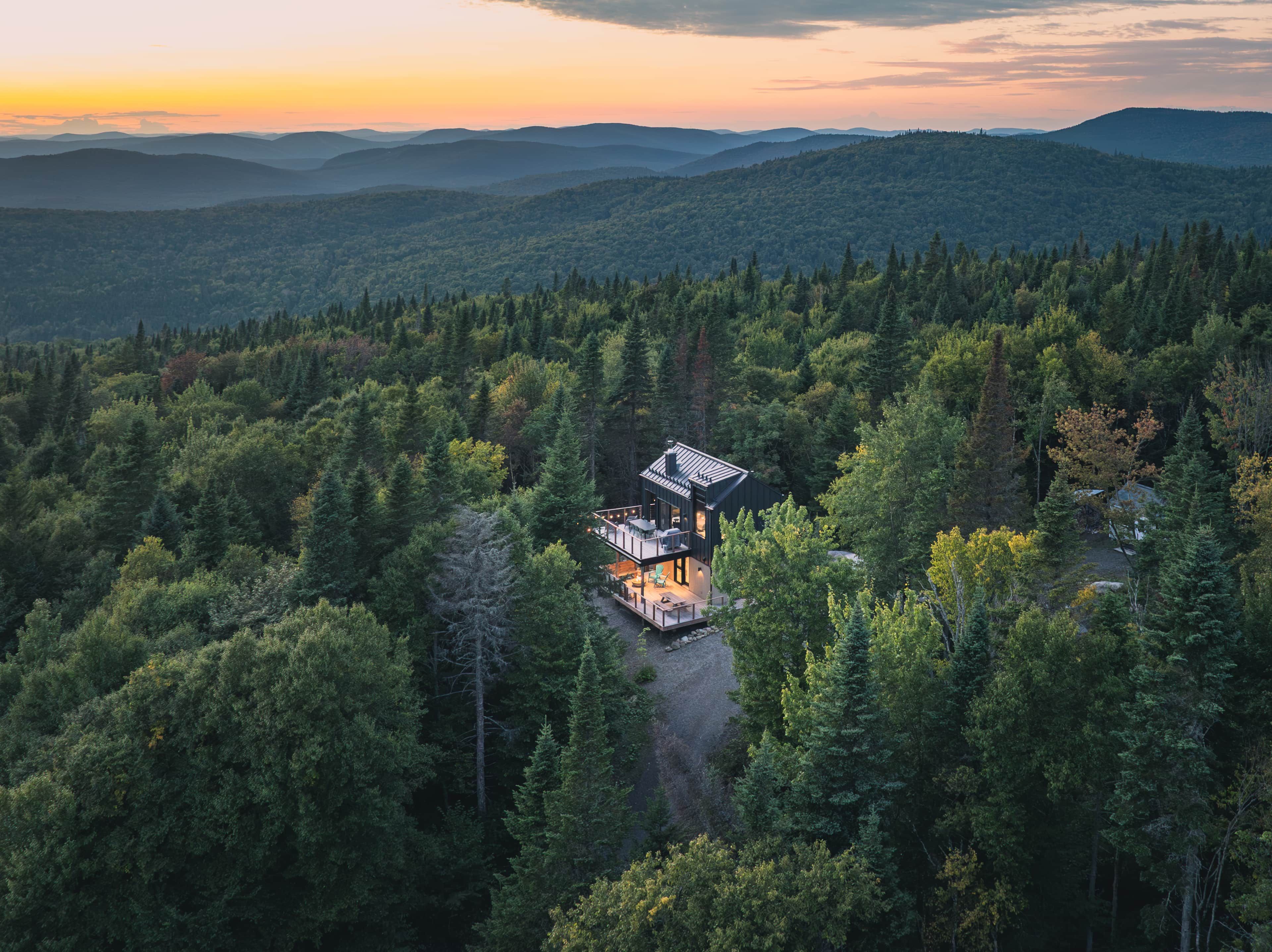 A remote cabin surrounded by dense forest, with a clear view of the surrounding mountains.