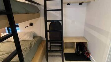 Habitación pequeña con una cama individual superpuesta, una escalera, un escritorio y una estantería.