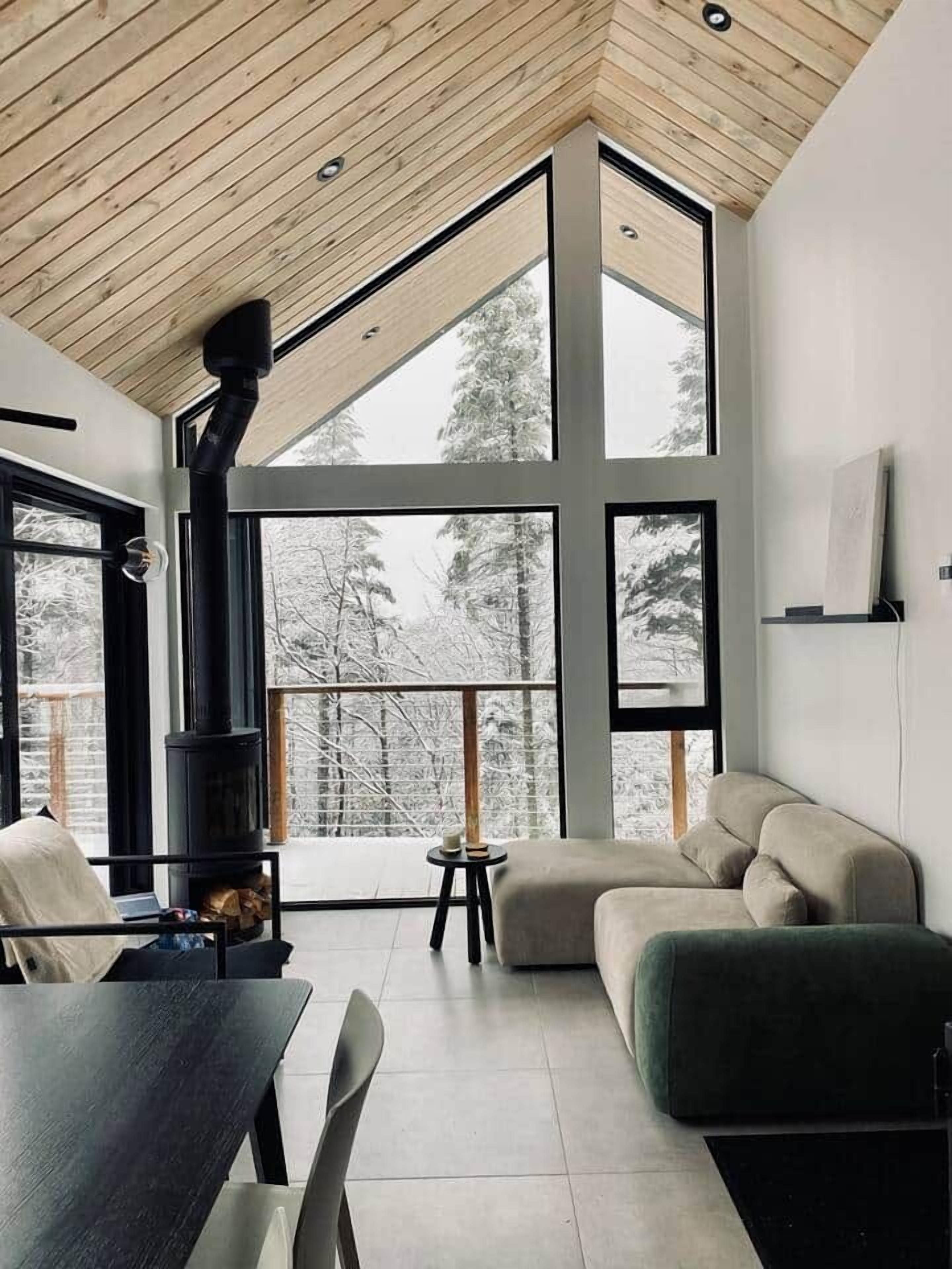 Un interior moderno con techo alto, ventanas grandes, chimenea y zona de estar.