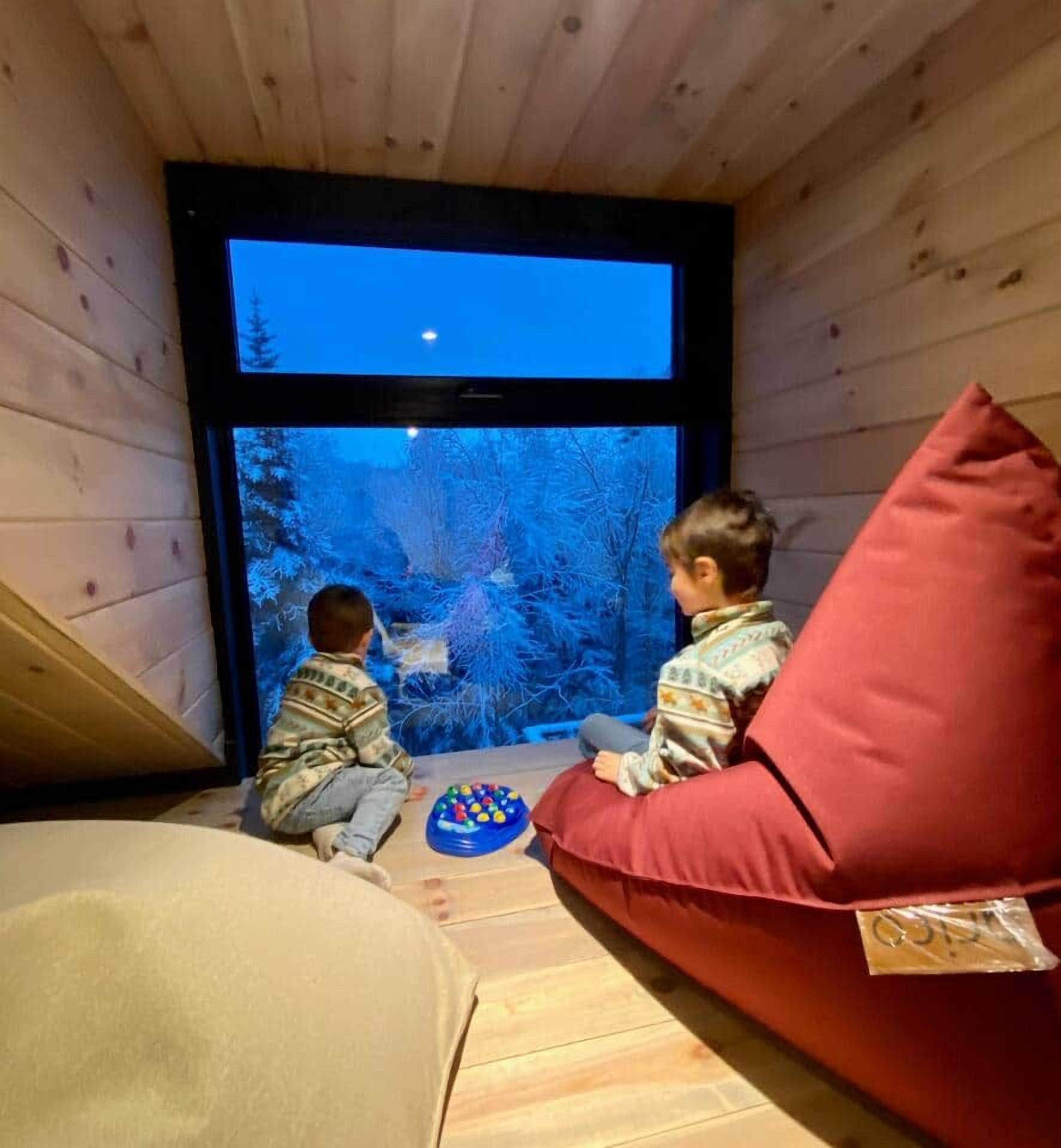 A room with a window, a red cushion, and a child playing with toys.