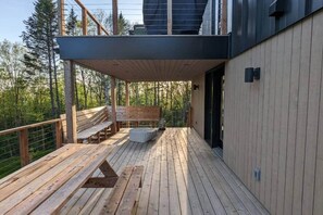 A wooden deck with benches and a stone seating area, overlooking a forested area. - MIST / Micro-Chalet / Nature Immersion (Capitale-Nationale)