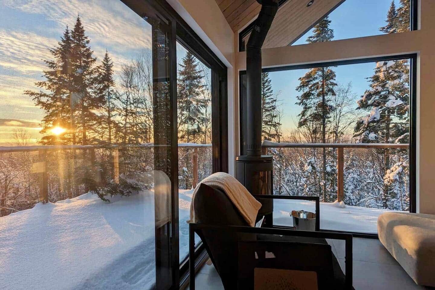 Una habitación con amplios ventanales que dan a un paisaje nevado, una chimenea y una zona de estar.