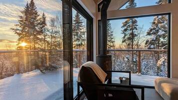 Una habitación con amplios ventanales que dan a un paisaje nevado, una chimenea y una zona de estar.