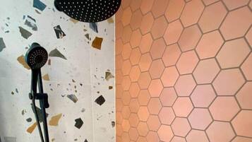 A shower with a handheld showerhead and a wall with a hexagonal tile pattern.