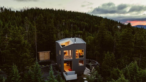 Une cabane moderne dotée d’un toit plat, de grandes fenêtres et d’une terrasse.
