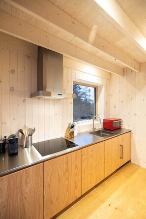 A modern kitchen with wooden cabinetry, a stainless steel sink, and a window providing natural light.