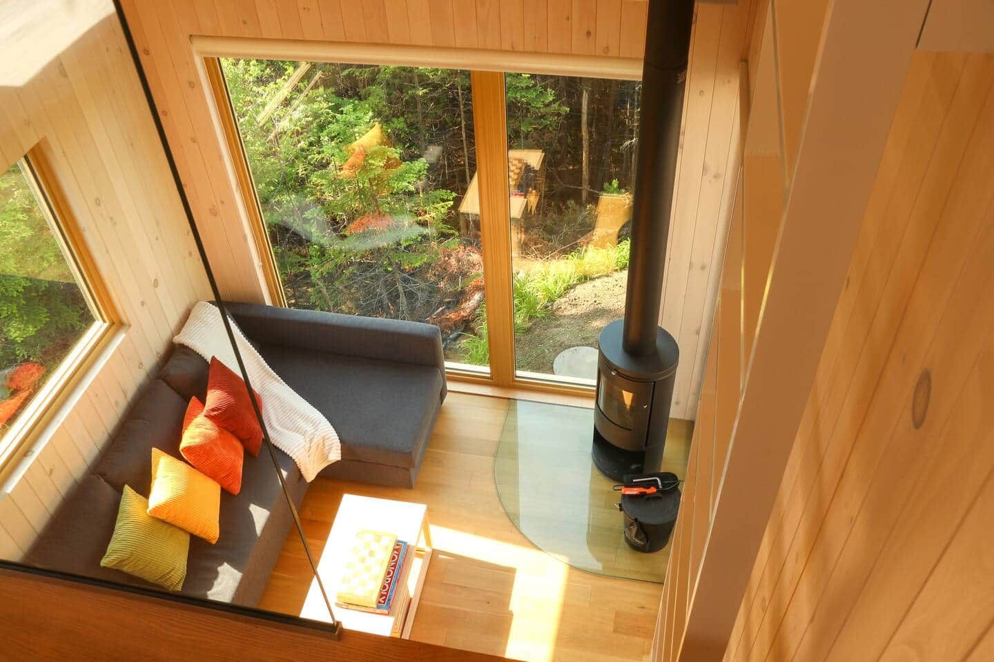 A cozy cabin interior with a sofa, a table, and a wood-burning stove.