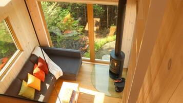 A cozy cabin interior with a sofa, a table, and a wood-burning stove.