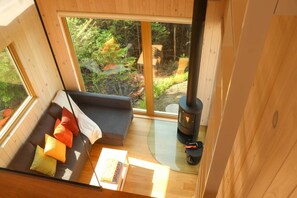 A cozy cabin interior with a sofa, a table, and a wood-burning stove.
