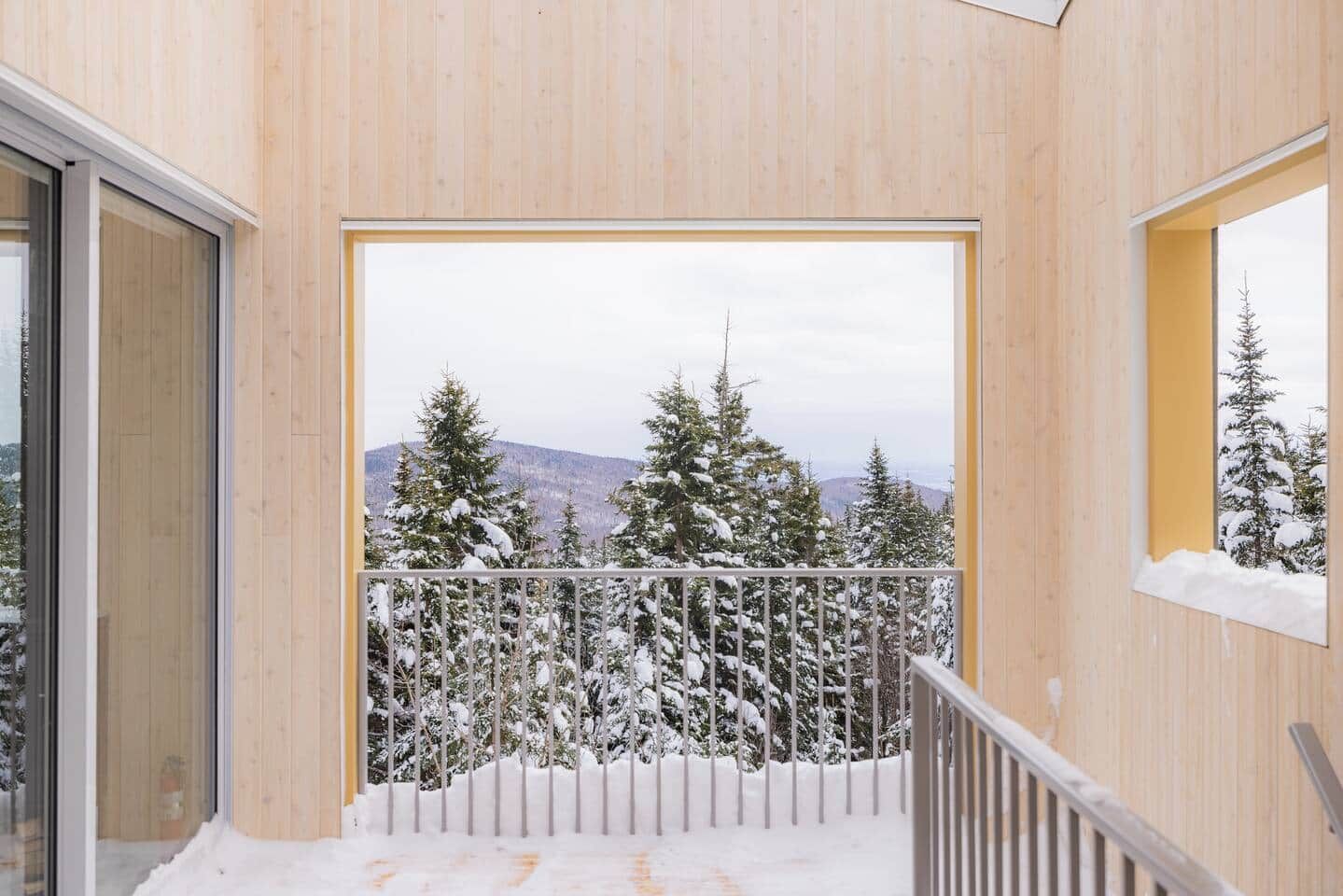A balcony with a view of snow-covered trees and a distant landscape.