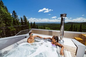Ein Whirlpool auf einer Terrasse mit Blick auf Wald und Berge.