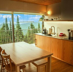 A modern kitchen with a large window overlooking a forested area.