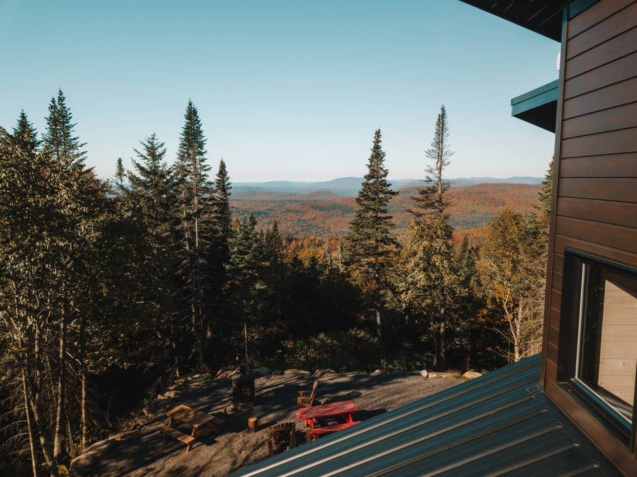 A cabin with a view of a forest and distant mountains.