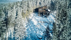 A modern cabin surrounded by a dense forest, with a clear sky above. - MIR / Micro-Chalet / Panoramic View (Capitale-Nationale)