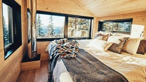 A cabin interior with a bed, windows, and a fireplace. - MIR / Micro-Chalet / Panoramic View (Capitale-Nationale)
