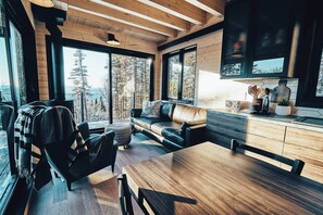 A modern interior with a wooden ceiling, a sofa, a dining table, and a kitchen area with a radio and decorative items.