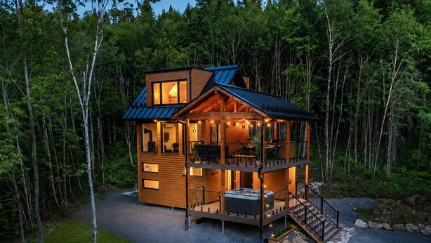 A two-story log cabin with a deck, outdoor seating, and a barrel. - MAO / Micro-Chalet / Private Thermal Experience near Quebec (Capitale-Nationale)