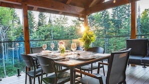 An outdoor dining area with a wooden deck, a table set for four, and a view of the forest. - MAO / Micro-Chalet / Private Thermal Experience near Quebec (Capitale-Nationale)