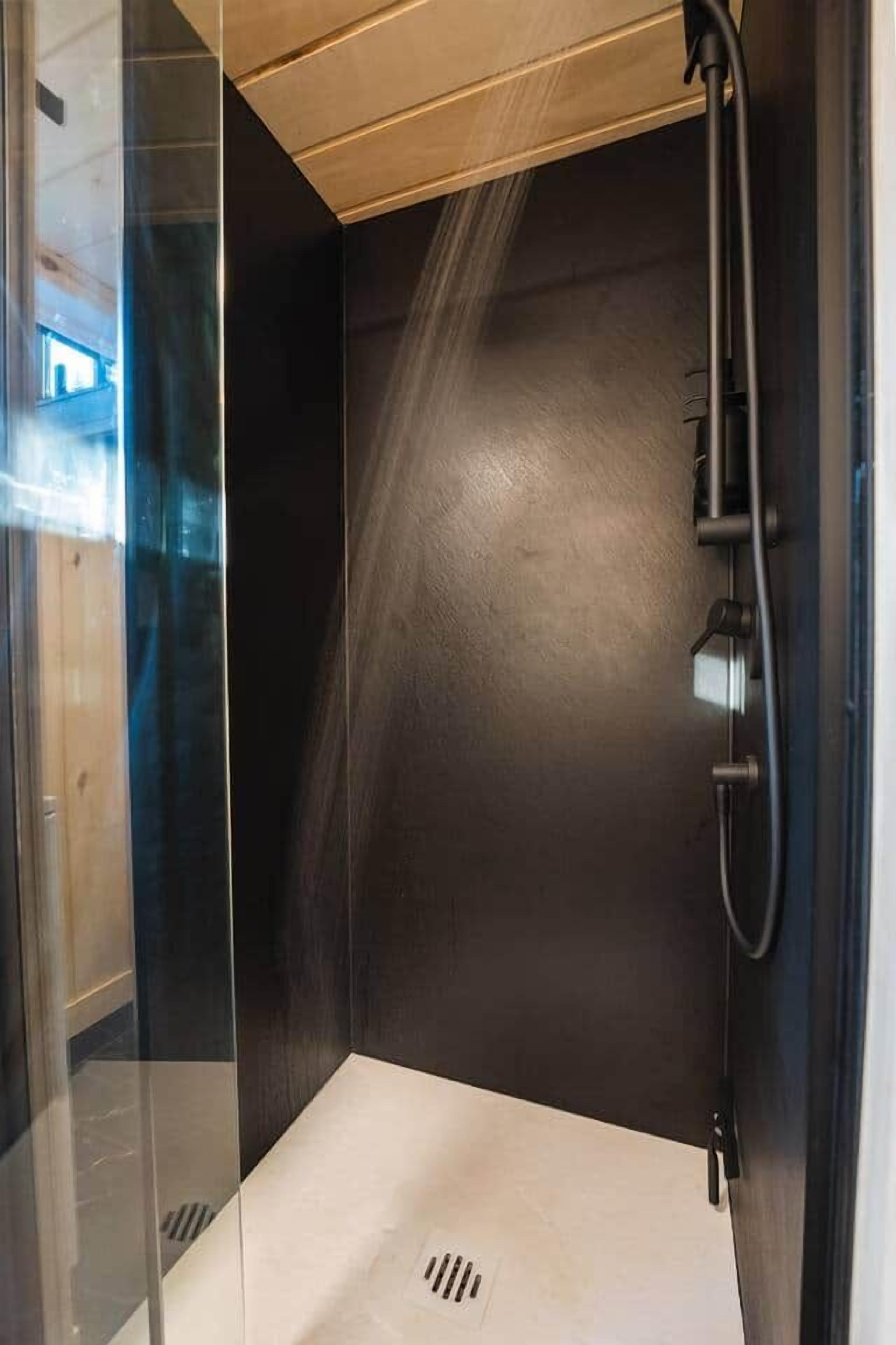 Eine moderne Duschkabine mit Glastür und schwarzem Innenraum.