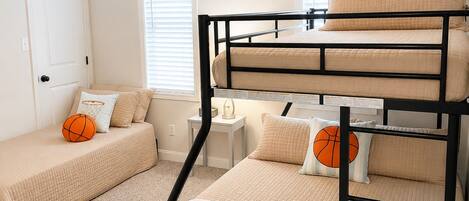 A bunk bed room with a ceiling fan, a door, and two windows with blinds.