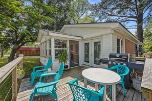 A covered patio with a grill, outdoor seating, and a view of a house in the background. - Turtle Time Groove - Waterfront Dock & Kayaks (New Bern)