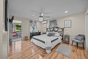 A bedroom with a bed, a nightstand, a chair, a ceiling fan, and a window with curtains. - Turtle Time Groove - Waterfront Dock & Kayaks (New Bern)