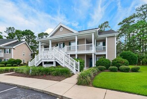 A multi-story residential building with a central staircase, multiple balconies, and a well-maintained lawn. - SeaShell Escape, Pool , Hot Tub & Golf Getaway (Pawleys Island)