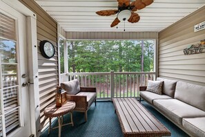 A covered porch with a ceiling fan, a clock, a welcome sign, wicker furniture, and a view of trees. - SeaShell Escape, Pool , Hot Tub & Golf Getaway (Pawleys Island)