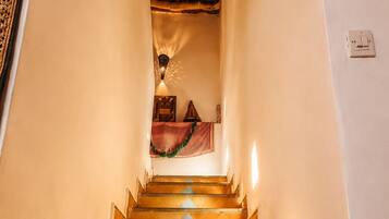 A staircase with a patterned floor leading to a room with a thatched ceiling.