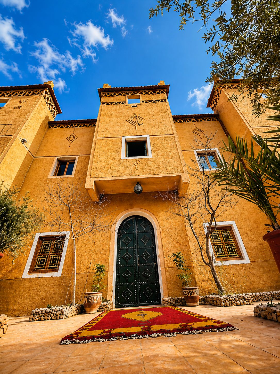 A building with a large central door, multiple windows, and a tiled courtyard.