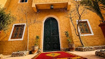 A building with a large central door, multiple windows, and a tiled courtyard.