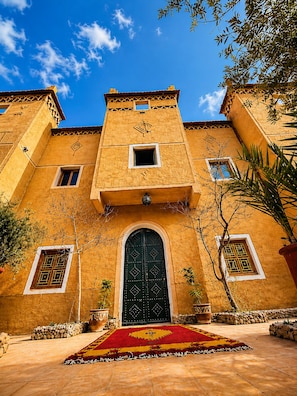A building with a large central door, multiple windows, and a tiled courtyard.