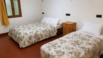 A bedroom with two single beds, a wooden nightstand, a wardrobe, and a window with curtains.