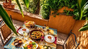 An outdoor dining area with a table set for a meal, surrounded by chairs and a decorative wall. - Riad Kasbah des Roches (Drâa-Tafilalet)