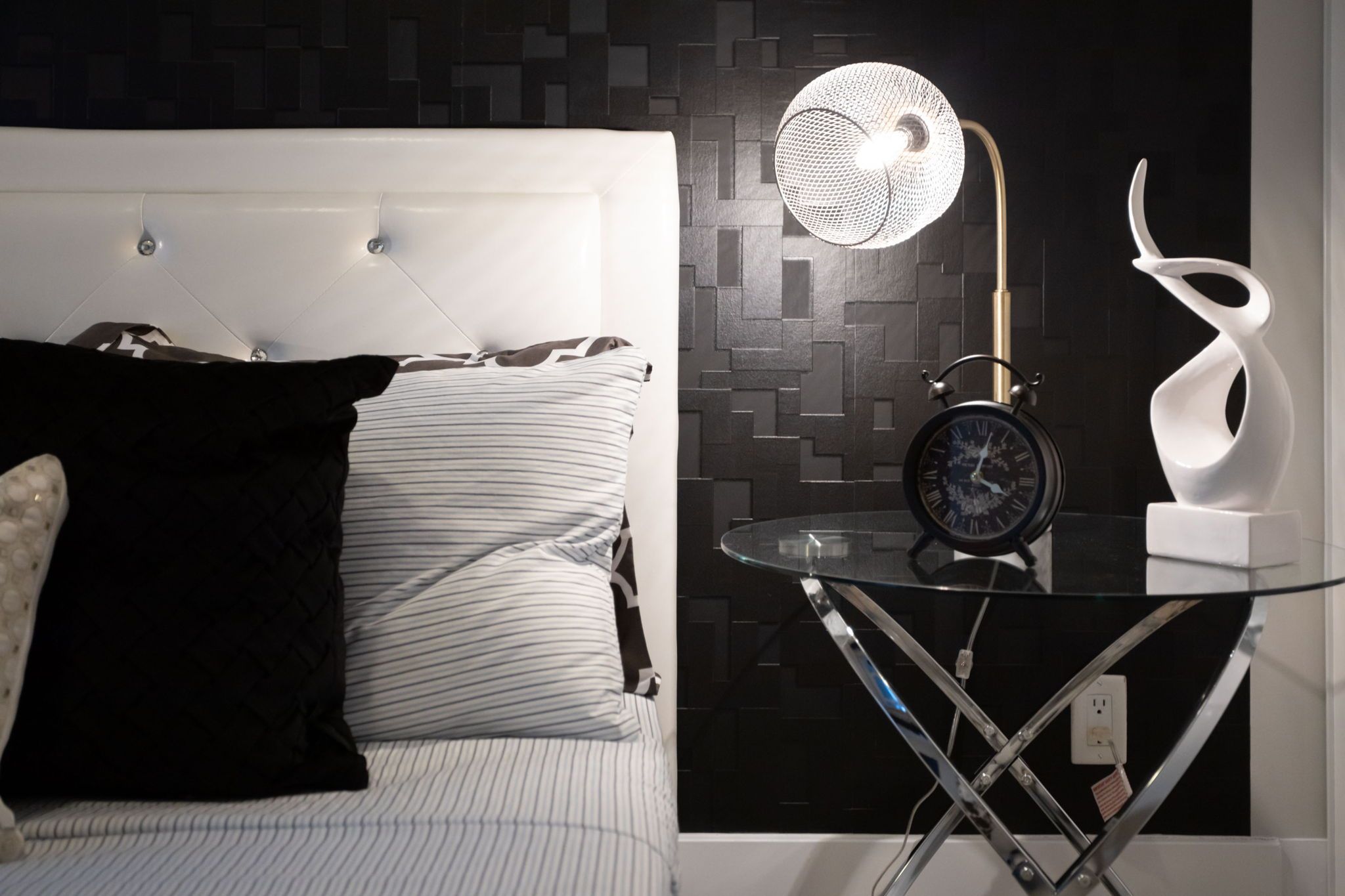 Ein modernes Schlafzimmer mit einem Bett, einem Nachttisch mit Lampe und einer Wanduhr.