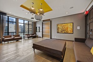 Ein modernes Hotelzimmer mit einem großen Bett, einer Sitzecke und großen Fenstern mit Blick auf die Stadt.