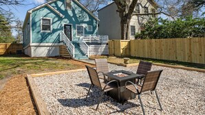 Una casa con fachada azul, una terraza de madera y un patio con mobiliario exterior.