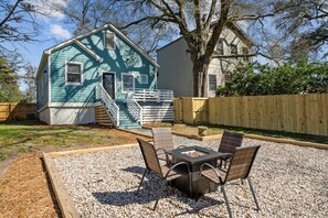 Una casa con fachada azul, una terraza de madera y un patio con mobiliario exterior.
