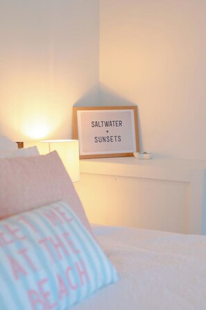 Une chambre à coucher avec un lit, une table de chevet avec une lampe et un tableau encadré accroché au mur.