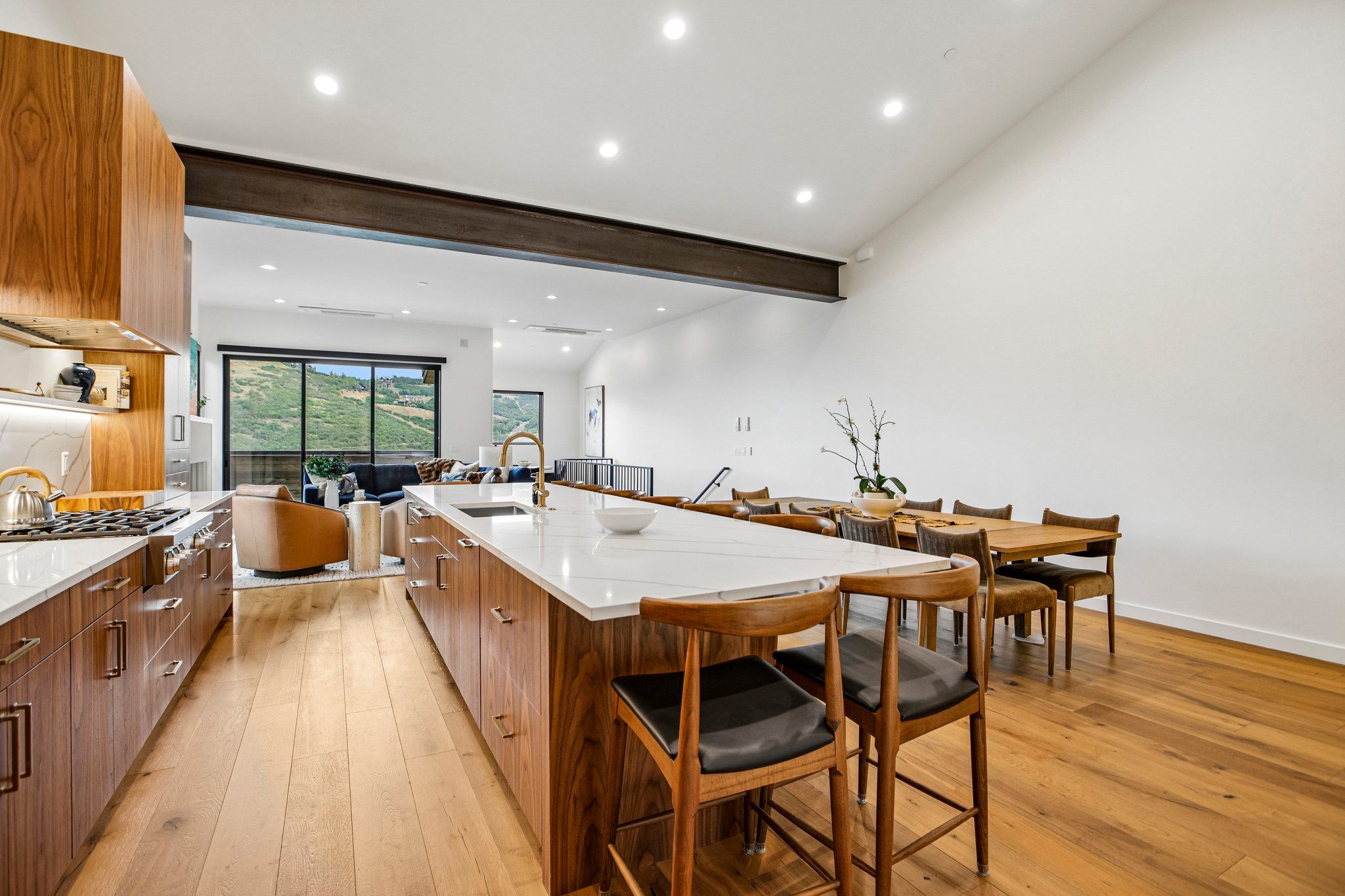 Una cocina moderna con armarios de madera, una isla central y un comedor con sillas de madera.