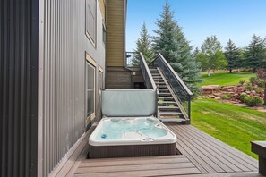 Ein Whirlpool auf einer Holzterrasse mit einer Treppe zu einem Gebäude.