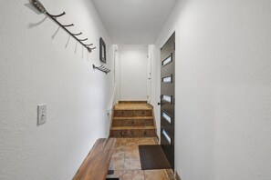 Ein Flur mit einer Holztreppe, die zu einer Tür mit mehreren Fenstern führt.