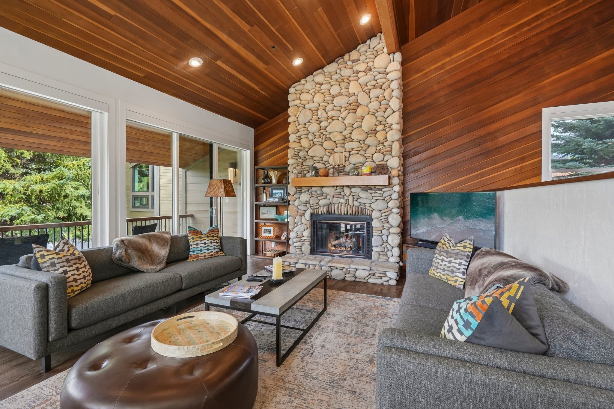 A modern living room with a stone fireplace, two sofas, a coffee table, and a bookshelf.