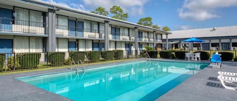 Un hotel con piscina, mobiliario exterior y cielo despejado.