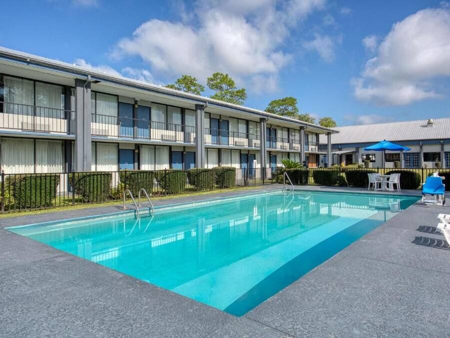 Een hotel met een zwembad, terras en heldere lucht.