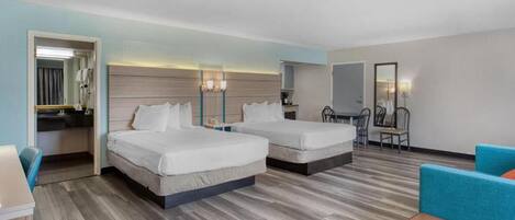 Habitación de hotel con dos camas, un escritorio, una silla y un pequeño rincón de descanso.