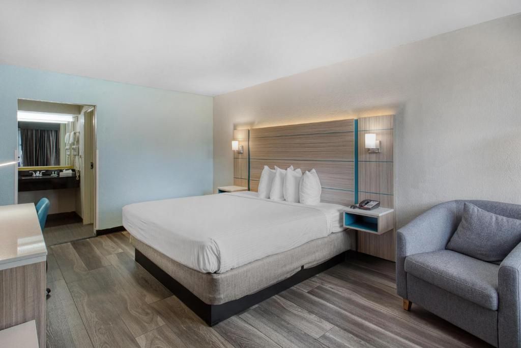 A hotel room with a large bed, bedside tables, a desk, and a chair.