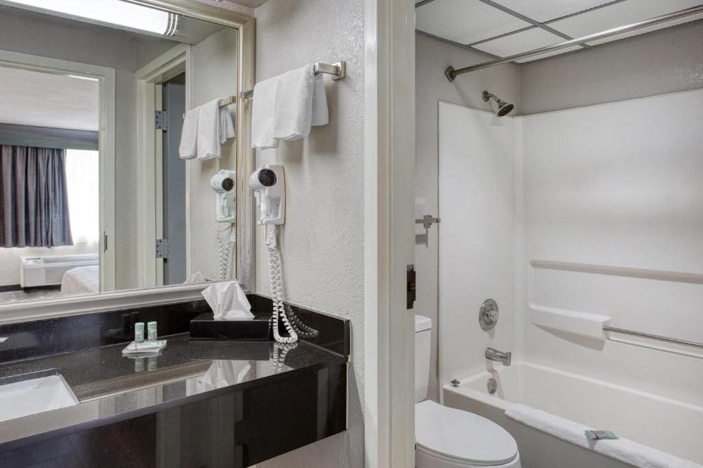 Un baño moderno con encimera negra, inodoro blanco y zona de ducha.