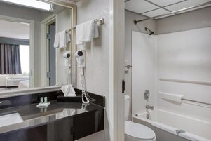 Un baño moderno con encimera negra, inodoro blanco y zona de ducha.