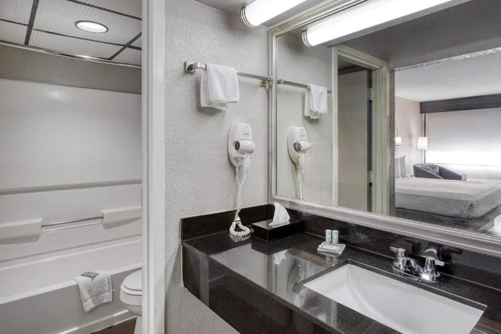 A modern bathroom with a large mirror, a black countertop, and a white sink.